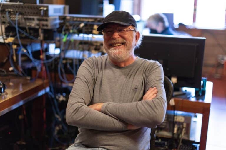 Bill O'Connell sits in a recording studio, looking relaxed and smiling.